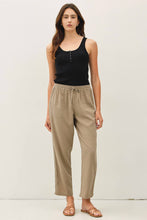 Load image into Gallery viewer, Woman wearing a black tank top and beige pants against a white background
