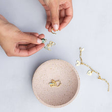 Load image into Gallery viewer, Person organizing jewelry on a speckled beige dish with a light gray background