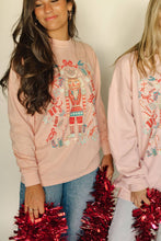 Load image into Gallery viewer, Two people wearing pink sweatshirts with festive designs, holding red tinsel.
