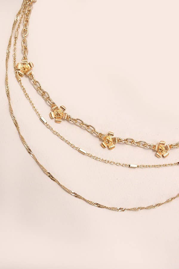 Three gold necklaces with charms on a beige background