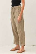 Load image into Gallery viewer, Woman wearing a black tank top and beige pants against a white background