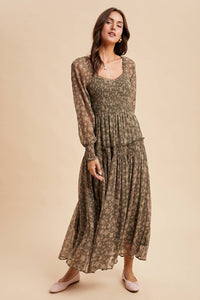 Woman wearing a long, patterned dress against a beige background