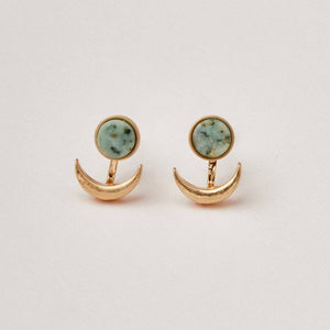 Gold earrings with green gemstones on a light gray background