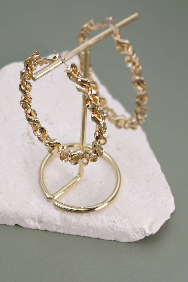 Gold hoop earrings on a white stone surface with a gray background