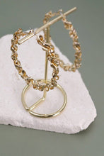 Load image into Gallery viewer, Gold hoop earrings on a white stone surface with a gray background