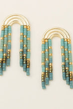 Load image into Gallery viewer, Pair of earrings with turquoise and gold beads on a light beige background