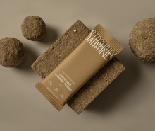 Load image into Gallery viewer, Brown energy bar with 'Satisfy' branding surrounded by chocolate balls on a brown background