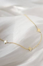 Load image into Gallery viewer, Gold star necklace on a white fabric background