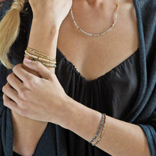 Load image into Gallery viewer, Close-up of a person wearing multiple bracelets and a necklace on a dark background