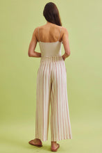Load image into Gallery viewer, Woman wearing a beige top and striped pants on a light green background
