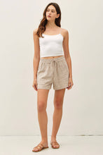 Load image into Gallery viewer, Woman wearing a white top and beige shorts against a plain background