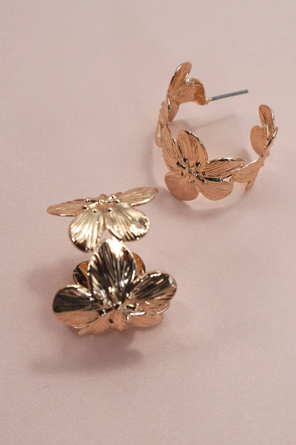 Gold floral hoop earrings on a light pink background