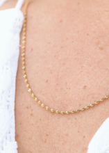 Load image into Gallery viewer, Gold chain necklace on a person wearing a white top.