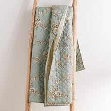 Load image into Gallery viewer, Light blue quilt with floral embroidery on a wooden ladder against a white background