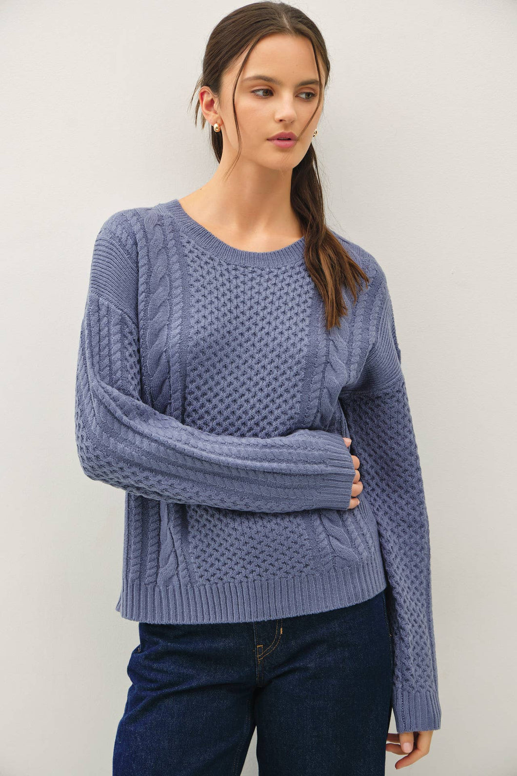 Woman wearing a blue knitted sweater against a plain background