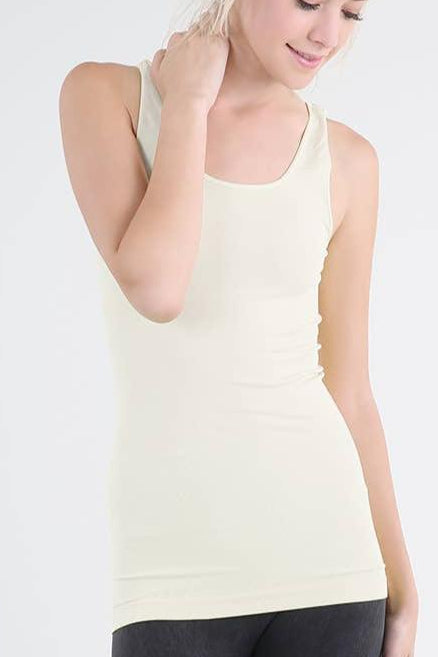 A woman is wearing a plain ivory jersey tank top with a scoop neck and wide straps.