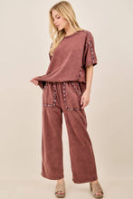 Load image into Gallery viewer, Woman wearing a maroon outfit with embellishments on a beige background