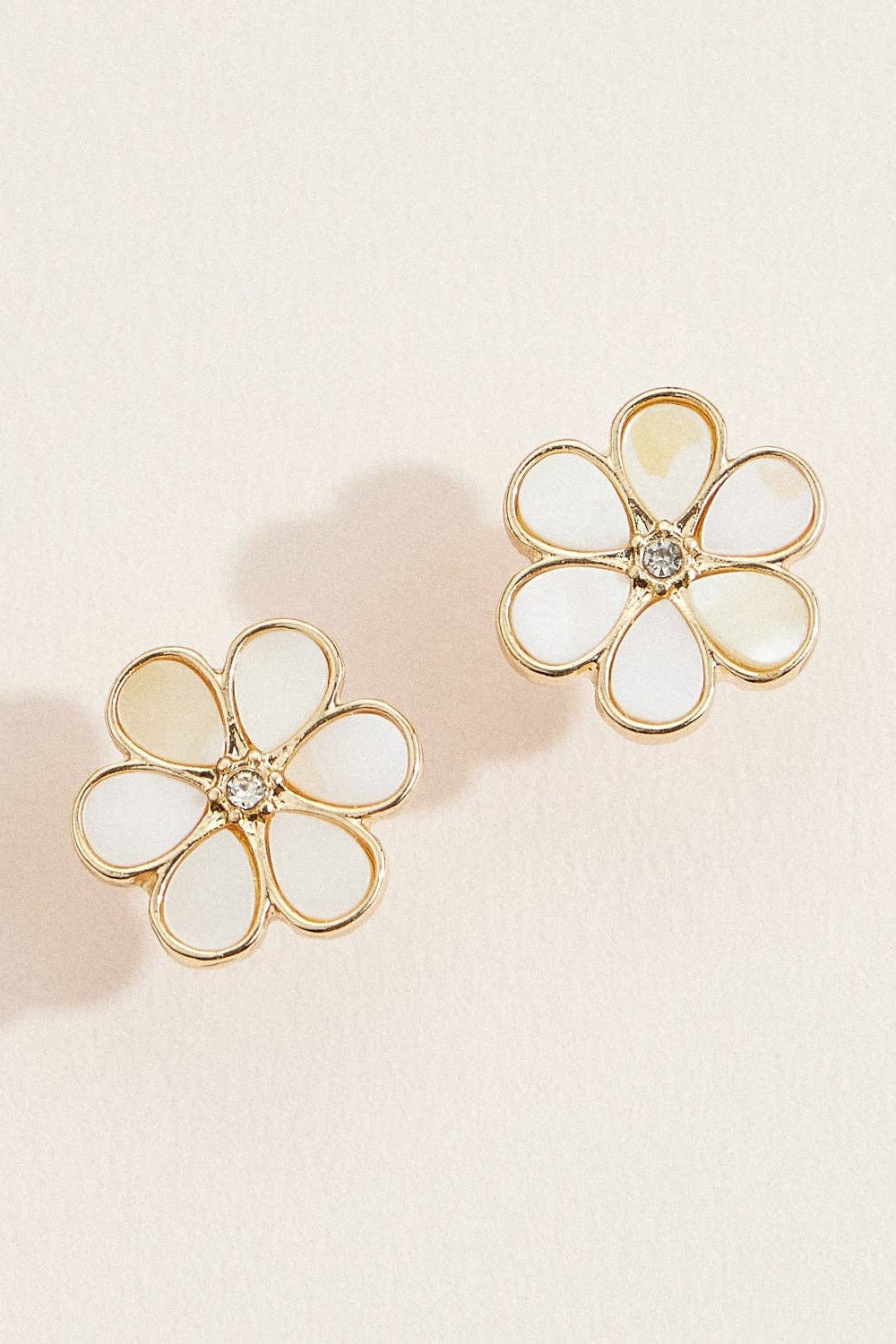 Flower-shaped earrings with gold frames and white centers on a light background
