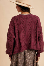 Load image into Gallery viewer, Person wearing a maroon cable knit sweater and a wide-brimmed hat on a beige background