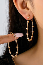 Load image into Gallery viewer, Gold hoop earrings being worn and held by a hand against a neutral background