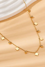 Load image into Gallery viewer, Gold necklace with flower-shaped pendants on a beige surface