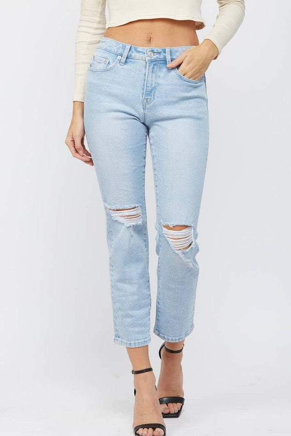 Woman wearing a cream long-sleeve top and light blue jeans on a white background