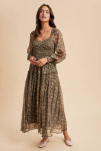 Load image into Gallery viewer, Woman wearing a long, patterned dress against a beige background