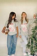 Load image into Gallery viewer, Two women wearing matching gray sweatshirts with a red and white design, standing next to a decorated Christmas tree.