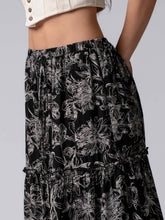 Load image into Gallery viewer, Black floral patterned skirt worn by a person on a gray background