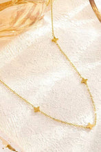 Load image into Gallery viewer, Gold star necklace on a textured white surface