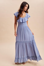 Load image into Gallery viewer, Woman wearing a blue tiered dress against a beige background