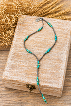 Load image into Gallery viewer, Turquoise beaded necklace on a wooden box with a blurred gold background