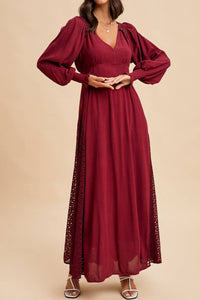 Woman wearing a burgundy dress with long sleeves on a beige background