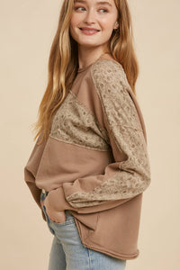 Woman wearing a brown sweater with lace details on a beige background