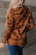 Load image into Gallery viewer, Person wearing a brown floral-patterned jacket against a gray tiled wall.