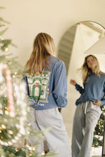 Load image into Gallery viewer, Person wearing a blue sweatshirt with a Christmas design, standing in front of a mirror with a decorated tree in the background.