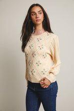 Load image into Gallery viewer, Woman wearing a beige floral sweater and blue jeans against a plain background