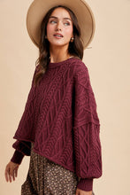 Load image into Gallery viewer, Woman wearing a maroon cable knit sweater and beige hat on a beige background