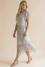 Load image into Gallery viewer, Woman wearing a floral dress against a beige background