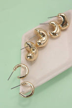 Load image into Gallery viewer, Gold hoop earrings on a pink stand against a light green background