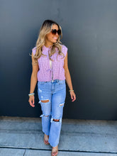 Load image into Gallery viewer, Woman wearing a purple knitted vest and ripped jeans against a dark wall.