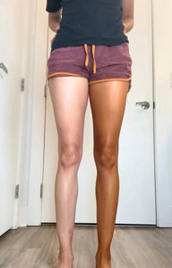 Person wearing purple shorts with orange drawstrings in a room.