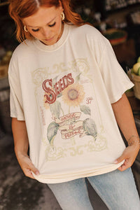 Person wearing a graphic t-shirt with a sunflower design and text.