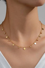 Load image into Gallery viewer, Gold necklace with small pendants on a person wearing a white top against a neutral background