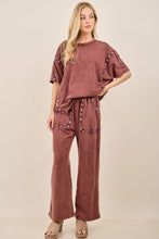 Load image into Gallery viewer, Woman wearing a brown outfit with embellishments on a beige background