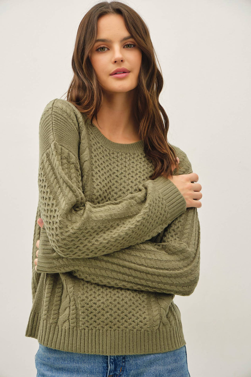 Woman wearing a green knitted sweater against a plain background