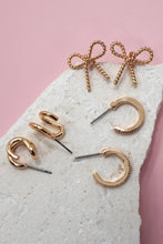 Load image into Gallery viewer, Gold earrings on a textured stone surface with a pink background