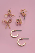 Load image into Gallery viewer, Gold earrings including bow and hoop designs on a pink background