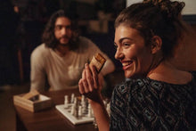 Load image into Gallery viewer, Woman playing chess with a man in a dimly lit room