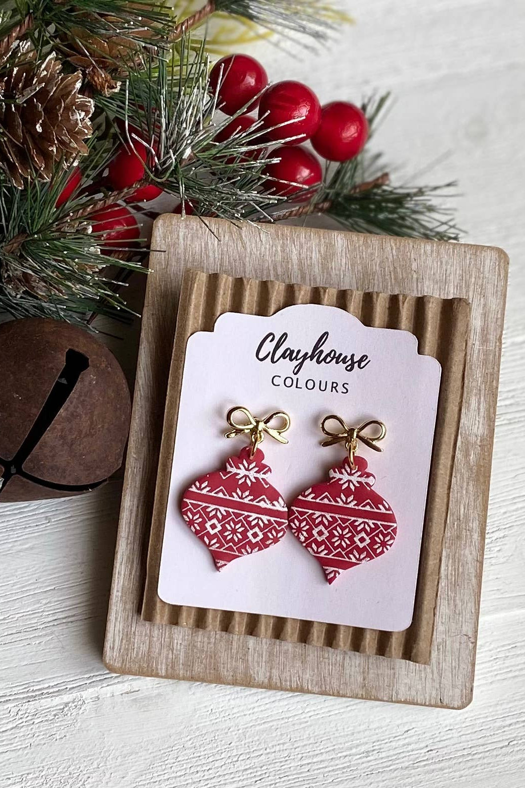 Red patterned earrings on a Clayhouse Colours card with Christmas decorations.